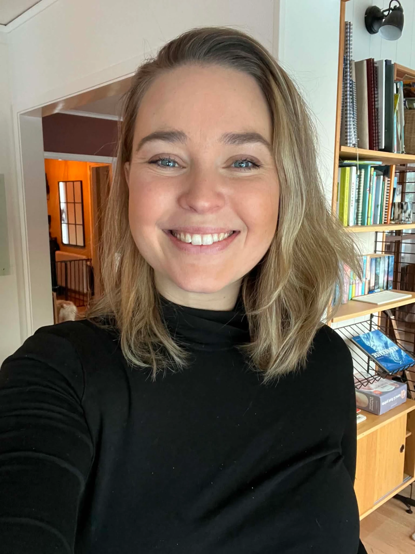 Amanda Arnold hemma framför bokhyllan